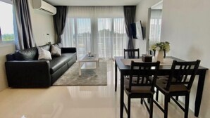 A modern living room with a sofa, dining table, chairs, and a TV.