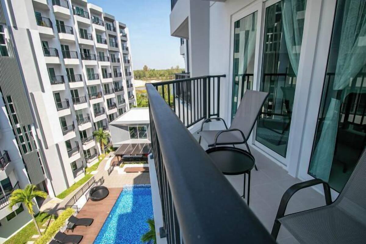 A balcony with a pool, lounge chairs, and a view of adjacent buildings.