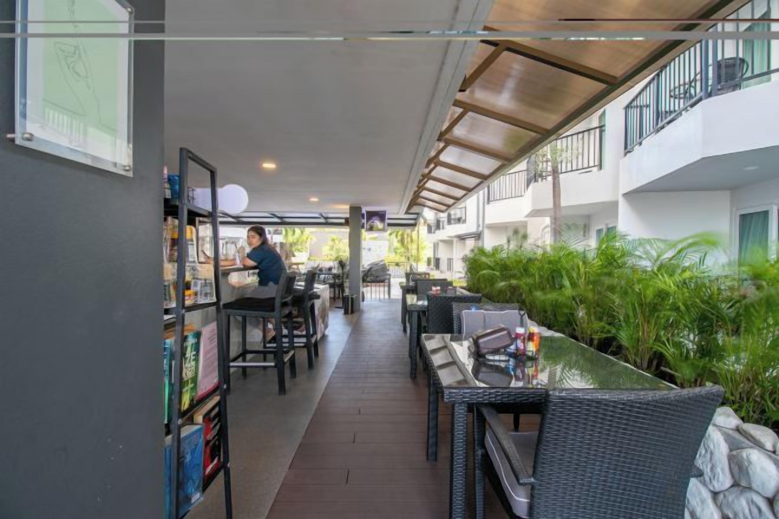 Un espacio al aire libre cubierto con asientos, una zona de bar y una persona atendiendo en una barra.