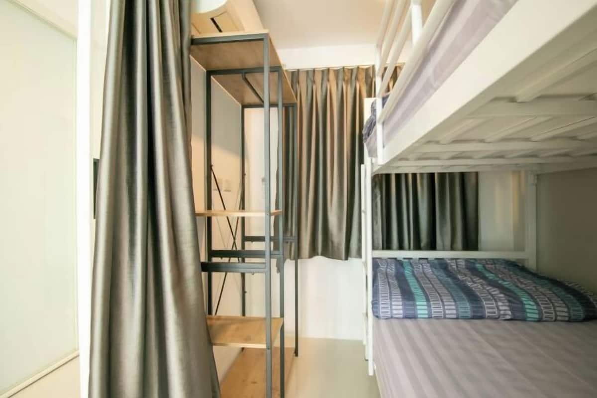 A bunk bed room with a metal ladder, a shelf, and a patterned bedspread.