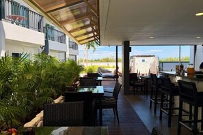 An indoor/outdoor dining area with tables and chairs, a view of the sea, and a covered walkway. - Mantra Beach Condominium MaePhim - 2 (Klaeng)