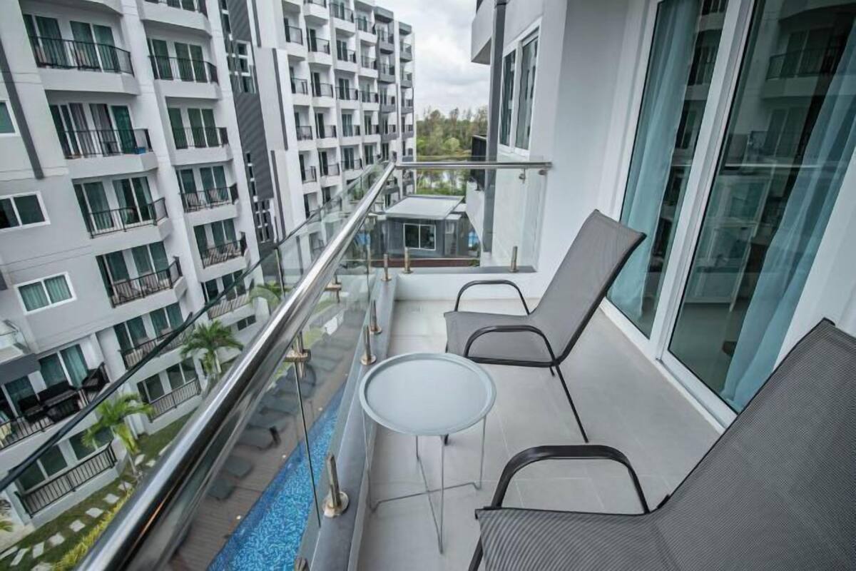 A balcony with a glass railing, a pool, and a table with chairs.