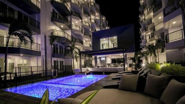 A modern hotel with a rooftop pool area, outdoor seating, and multiple balconies.