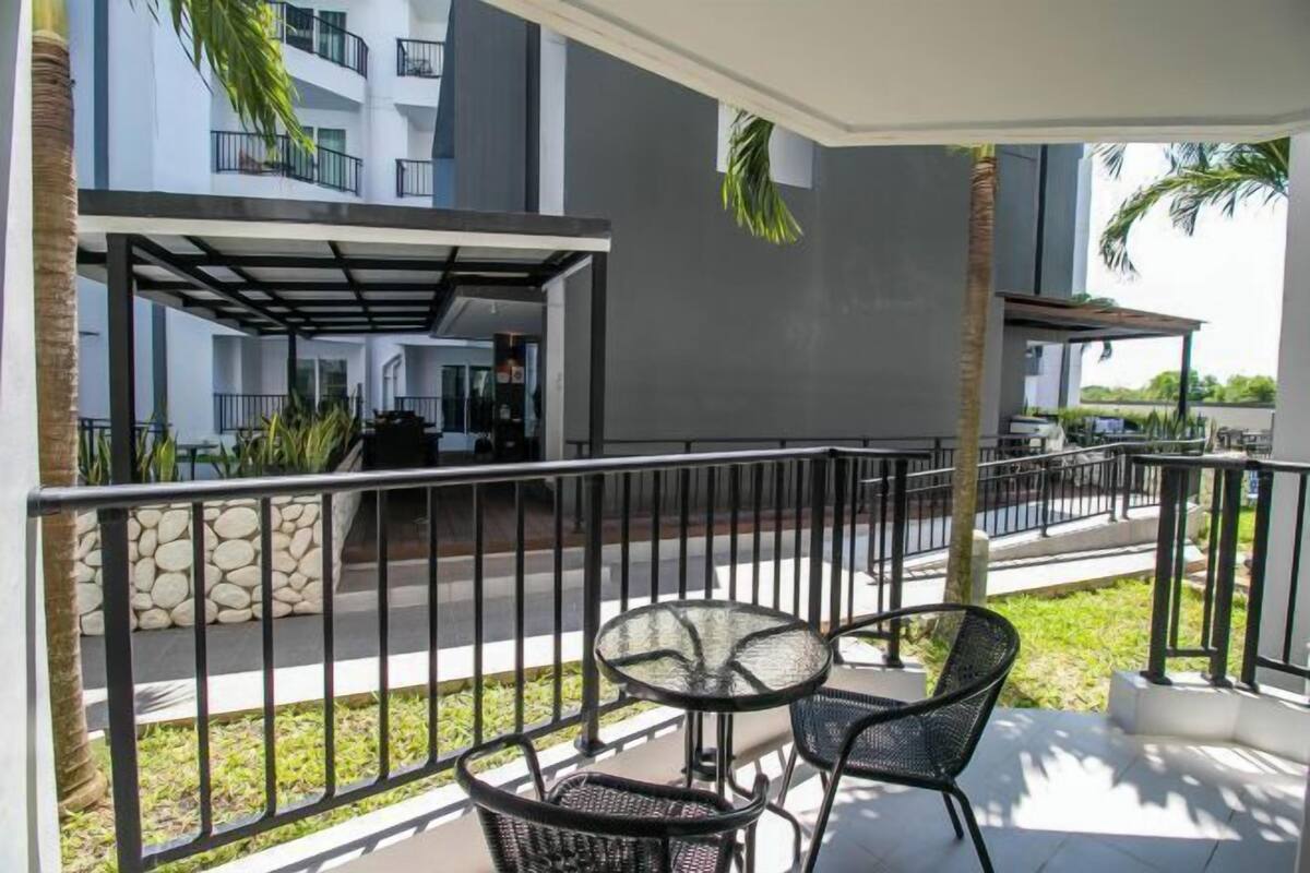 A balcony with a glass table and chairs, a stone wall, and a view of a building with balconies.