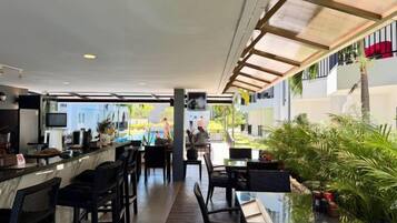 Un área de bar al aire libre con asientos, una barra y vistas a la calle.