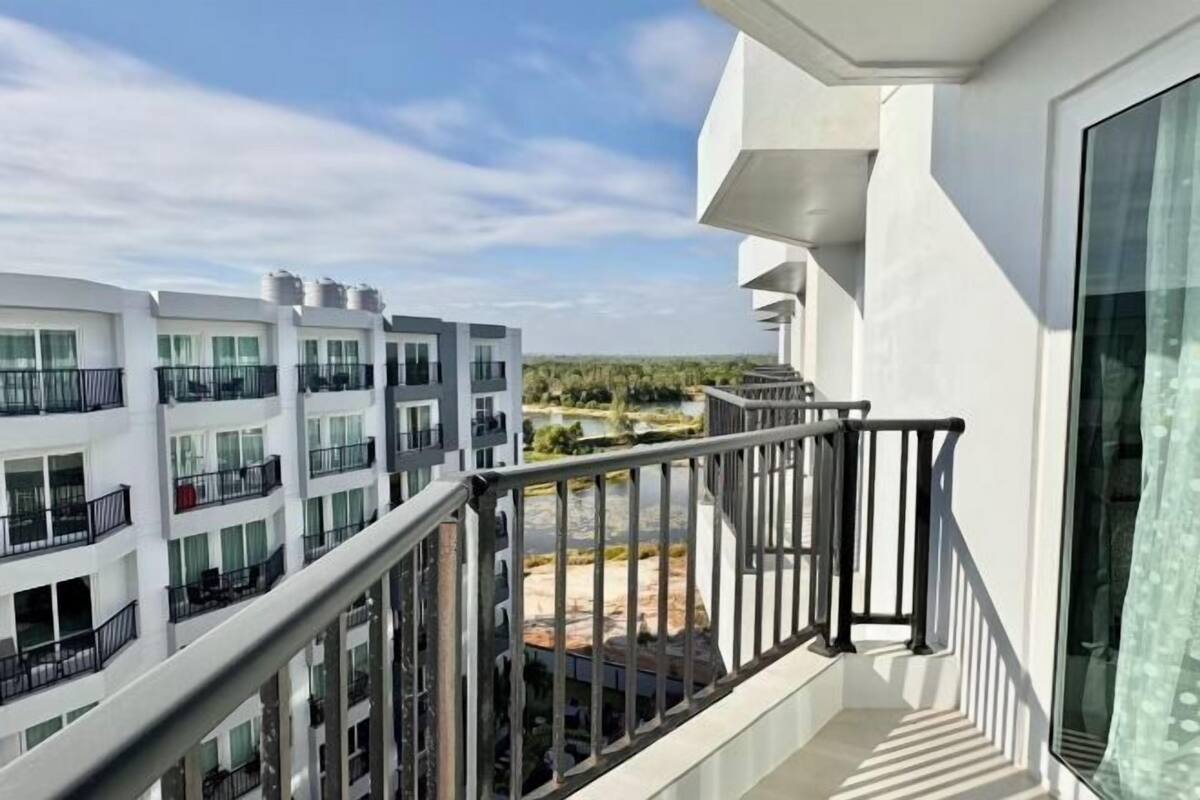A modern building with balconies, large windows, and a view of a landscaped area.