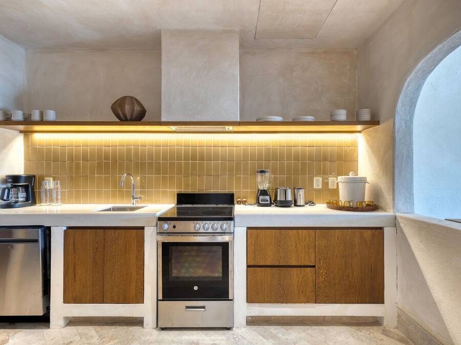 Uma cozinha compacta com forno embutido, cafeteira e pia.