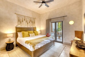 Une chambre spacieuse avec un grand lit, un ventilateur de plafond, une vue sur l’extérieur et une table de chevet en bois.