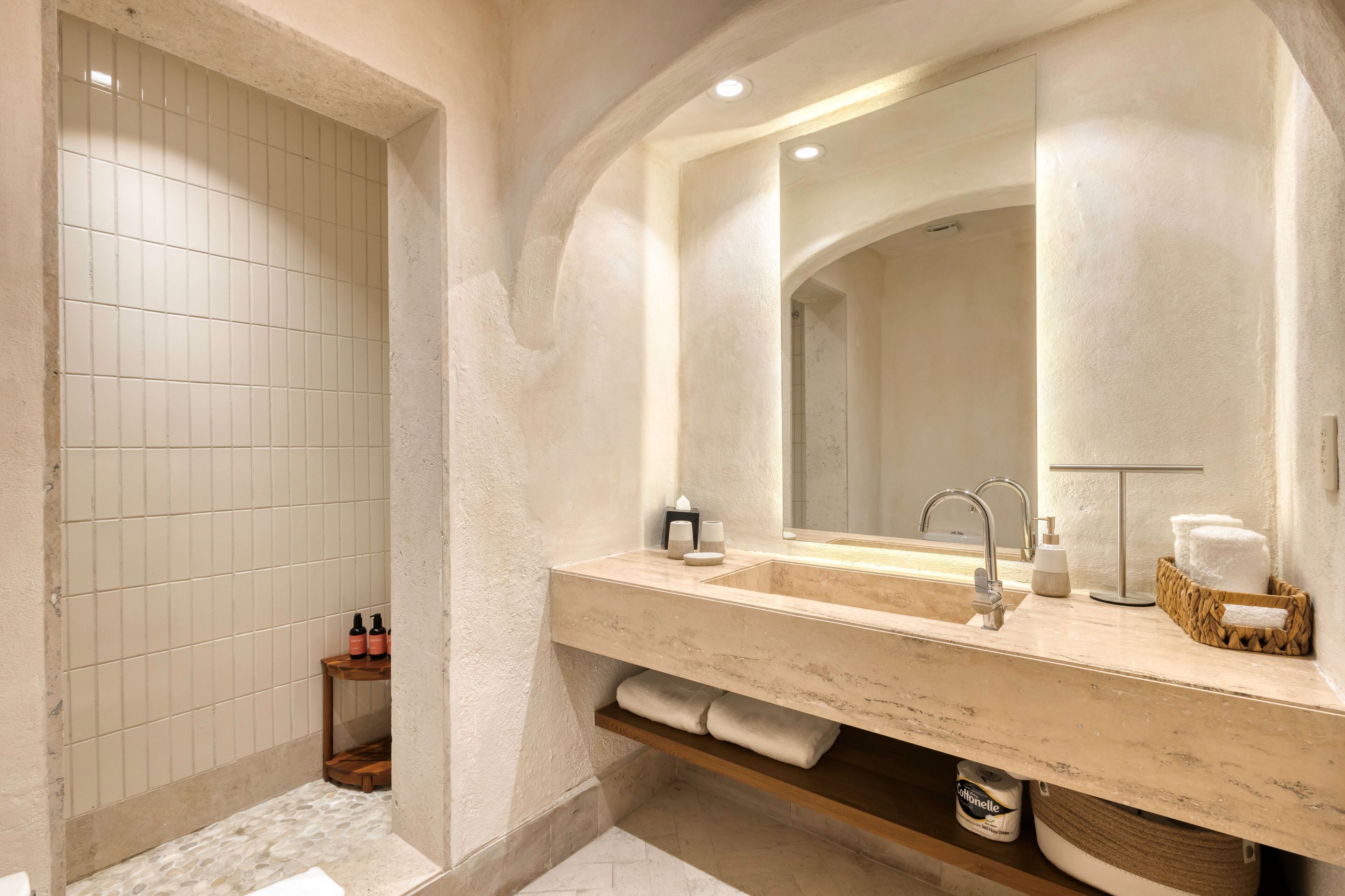 A bathroom with a large mirror, a sink, and a shower area.