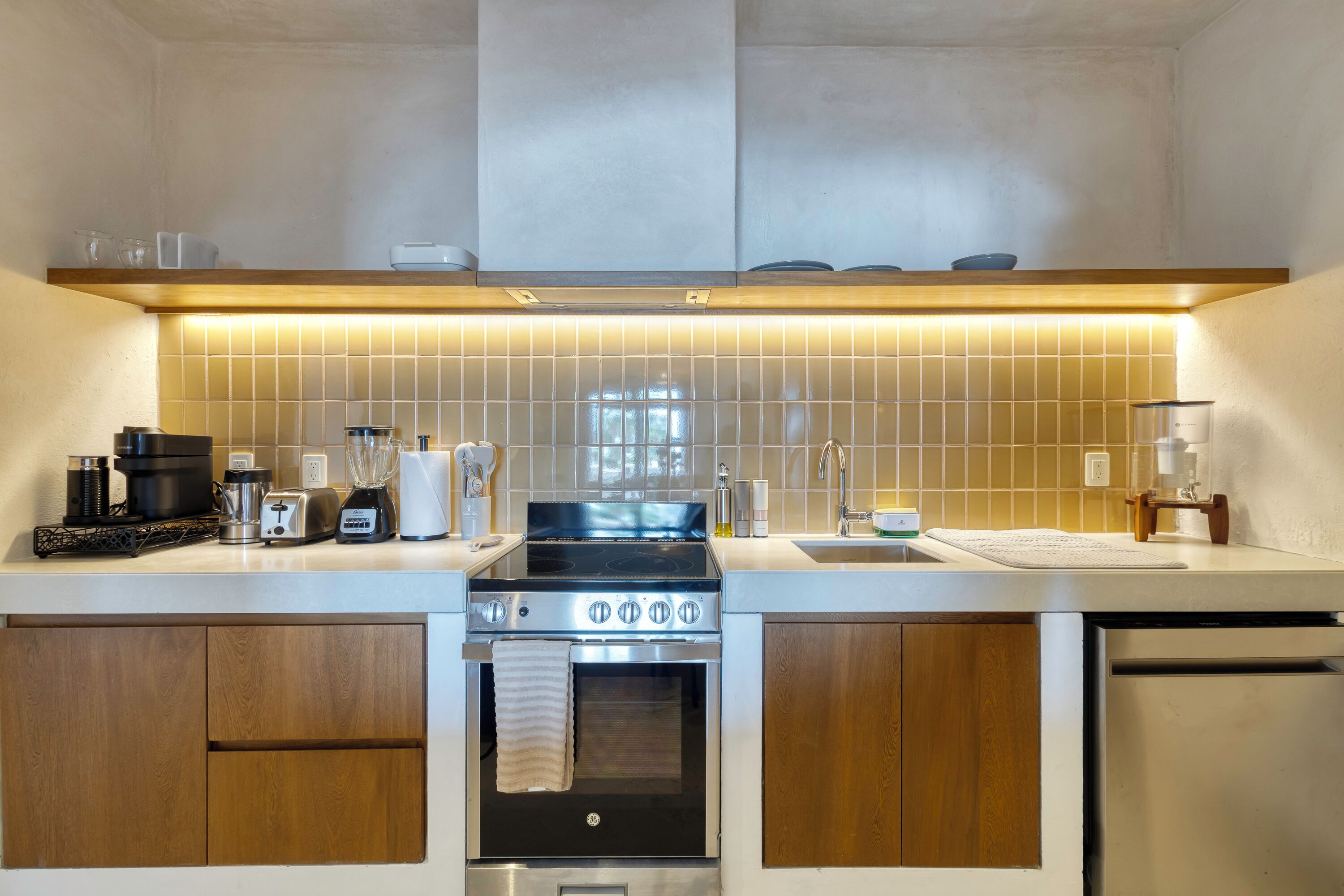 A modern kitchen with a stainless steel stove, oven, and dishwasher, wooden cabinets, and a tiled backsplash.