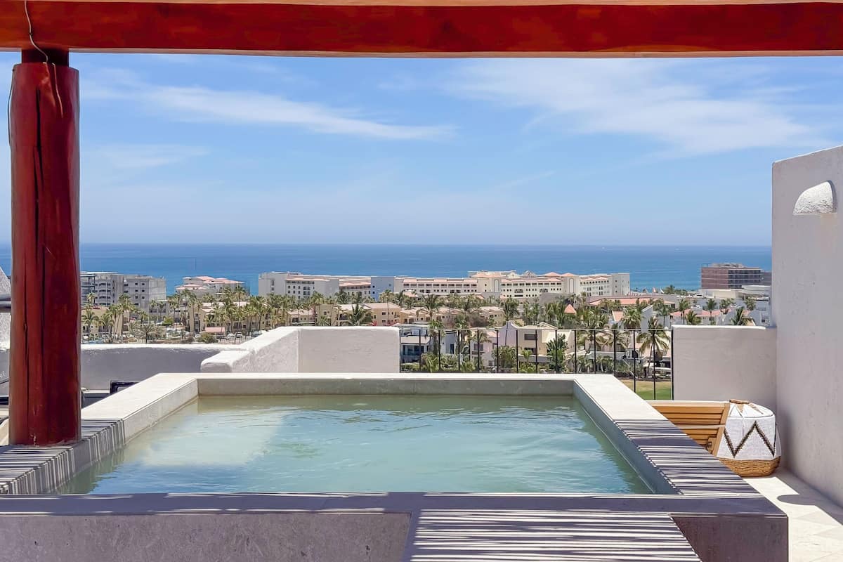 Una piscina en la azotea con vistas al océano y al paisaje urbano.