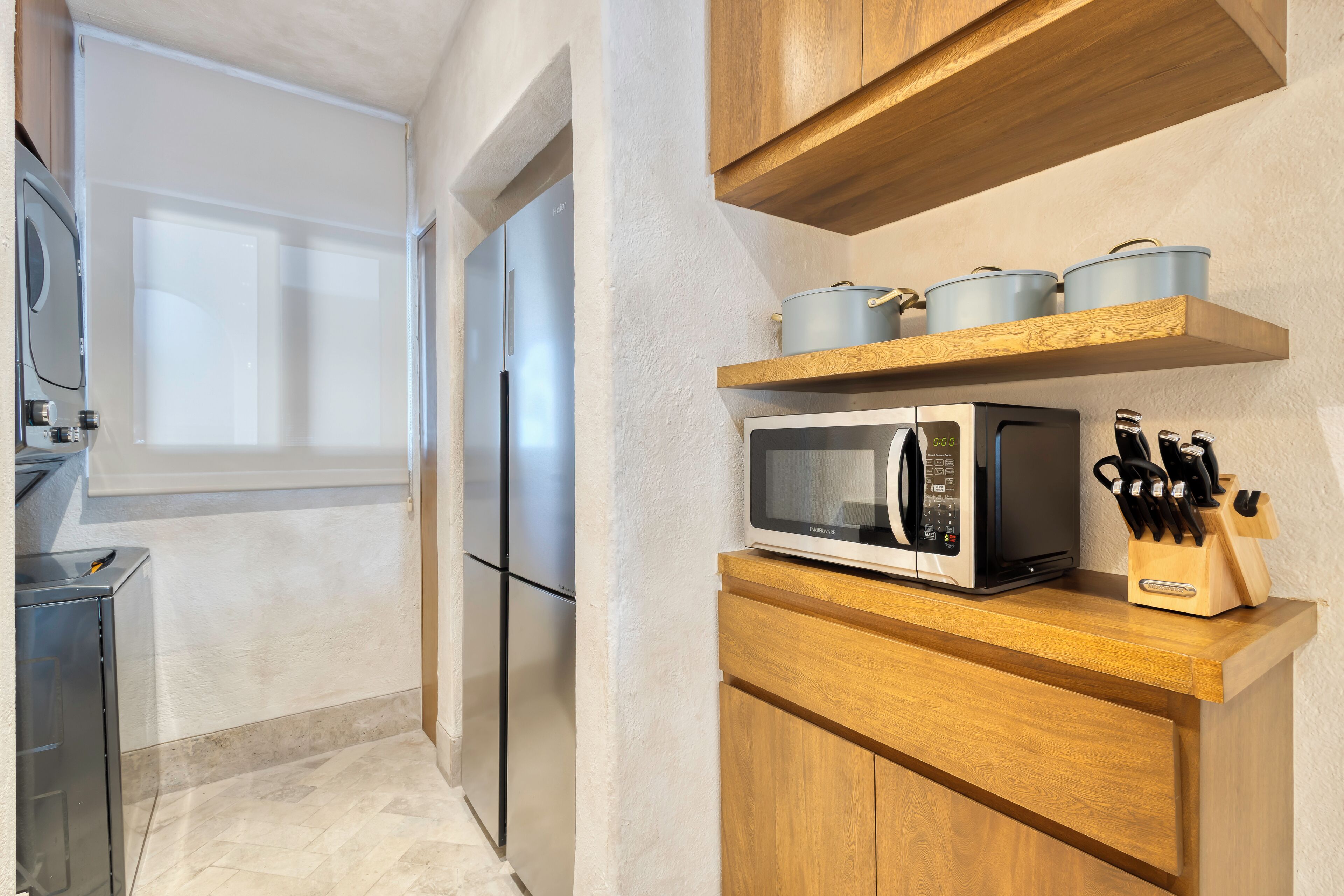 A kitchen with a microwave, wooden cabinets, and a knife block.