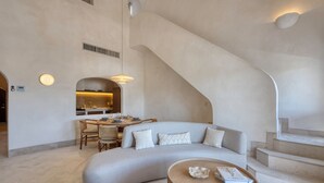 Ein modernes Interieur mit einer gebogenen Couch, einem Essbereich und einer Treppe.