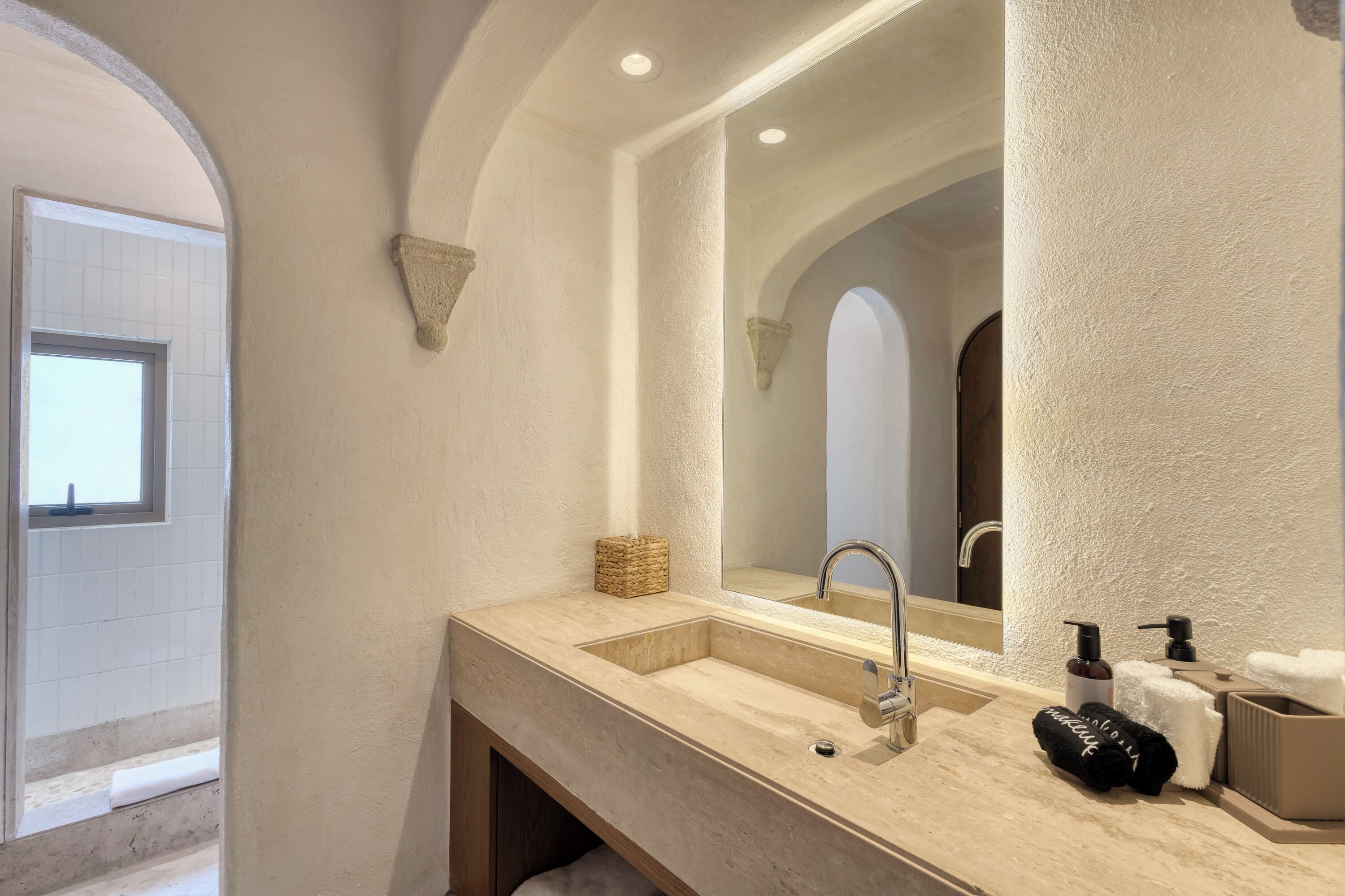 Une salle de bain avec un lavabo beige, un grand miroir et un porte-serviettes.