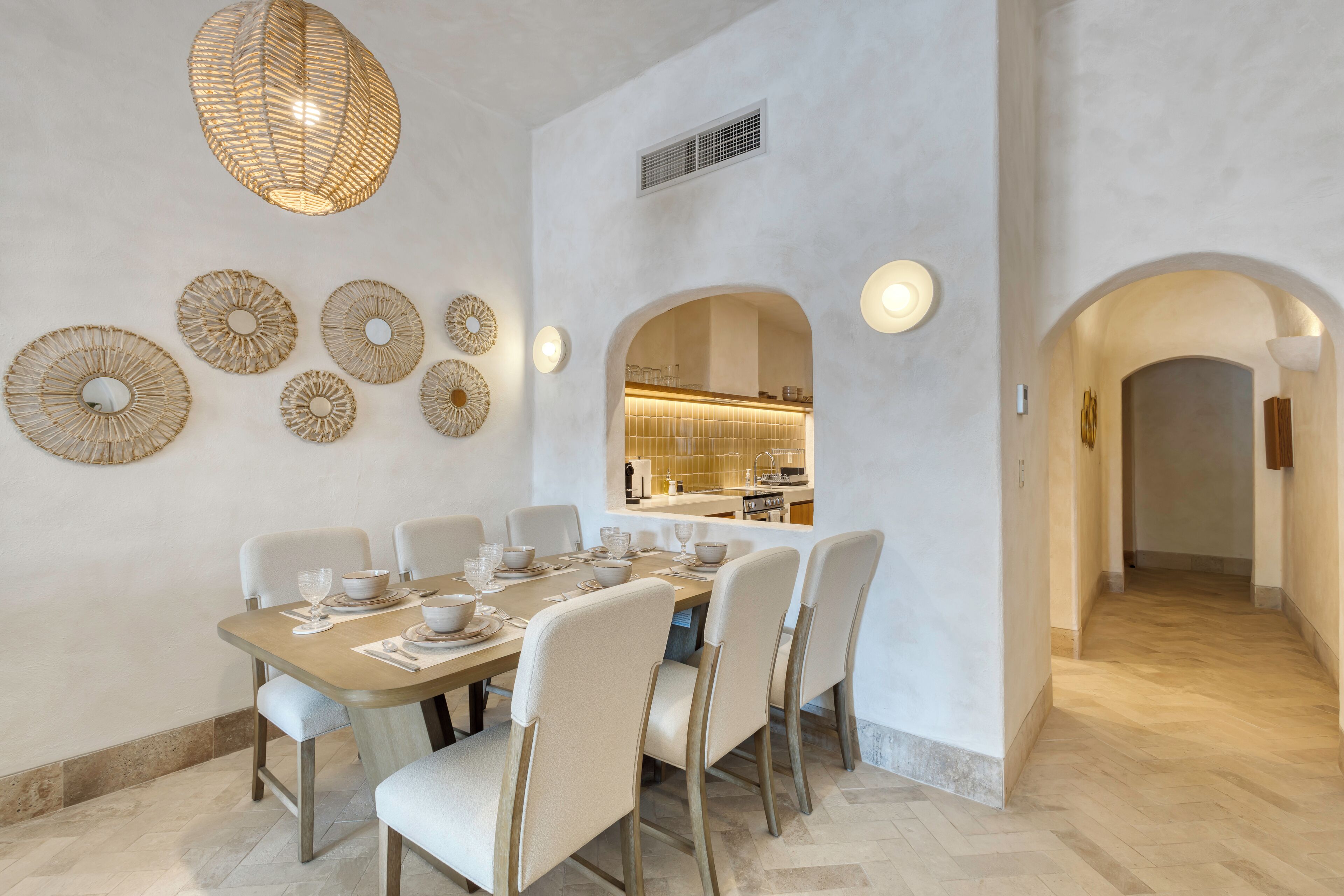 Uma sala de jantar com uma mesa comprida, várias cadeiras e arte decorativa na parede.