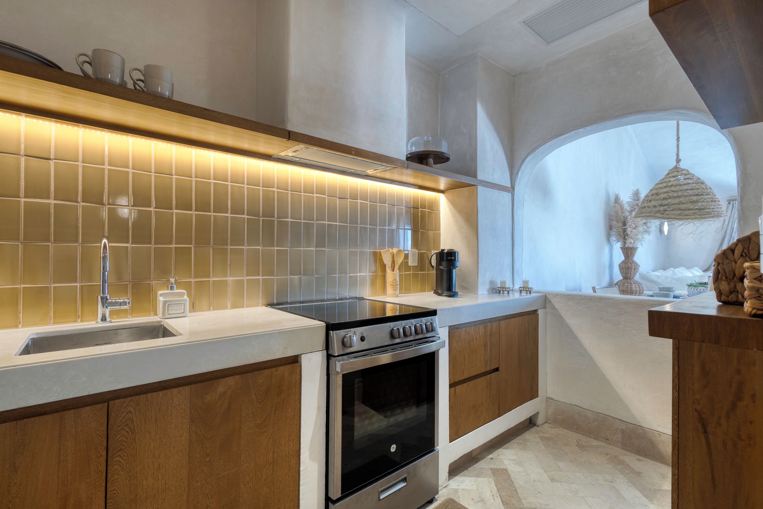 A modern kitchen with a built-in oven, a sink, and a large window.