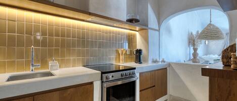 Una cocina moderna con horno empotrado, un lavabo y un ventanal grande.