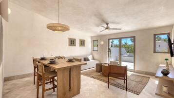 A spacious kitchen with a wooden island, a ceiling fan, and large windows offering a view of the outdoors.