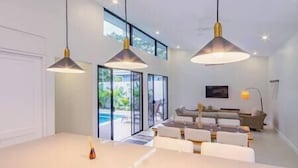 A modern kitchen with a large island, pendant lighting, and a view of a pool and outdoor seating area.