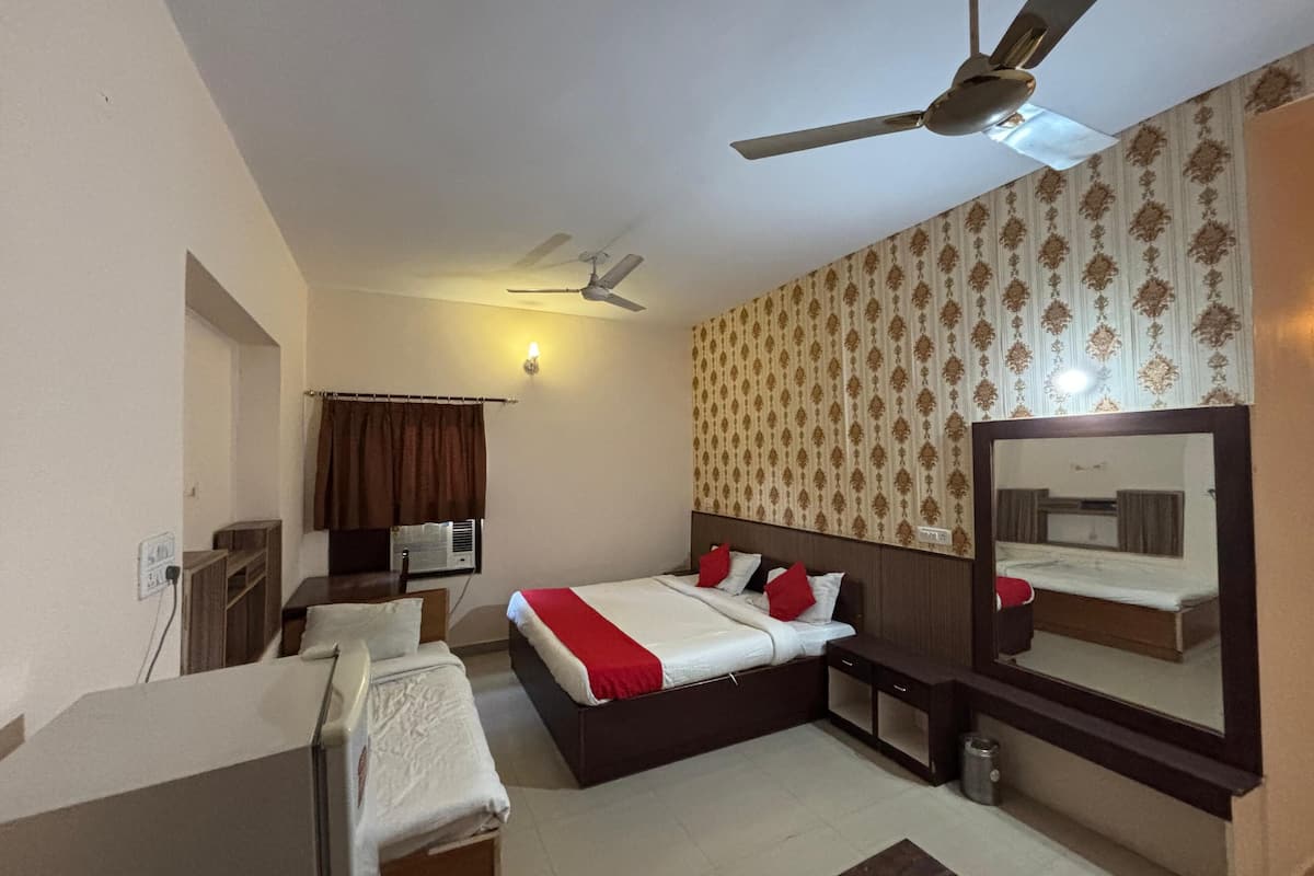 Une chambre d’hôtel équipée d’un lit, d’une table de chevet, d’un miroir, d’un ventilateur de plafond et d’un climatiseur fixé au mur.