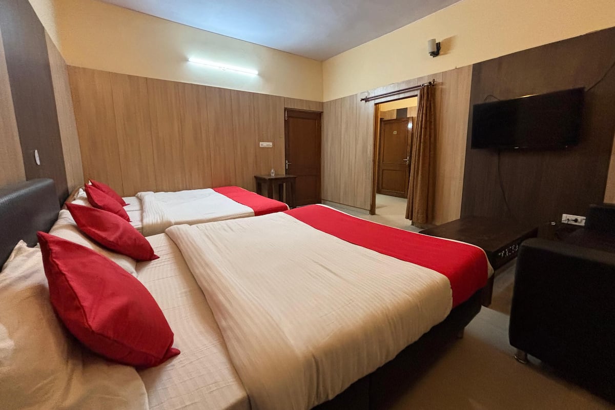 Une chambre d’hôtel avec deux lits, une télévision, une petite table et une porte donnant sur une autre pièce.