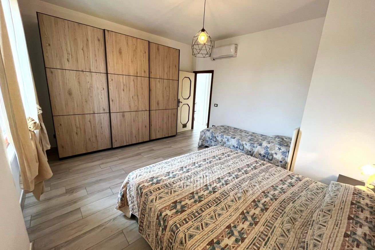 A bedroom with a bed, a wardrobe, and a hanging light fixture.