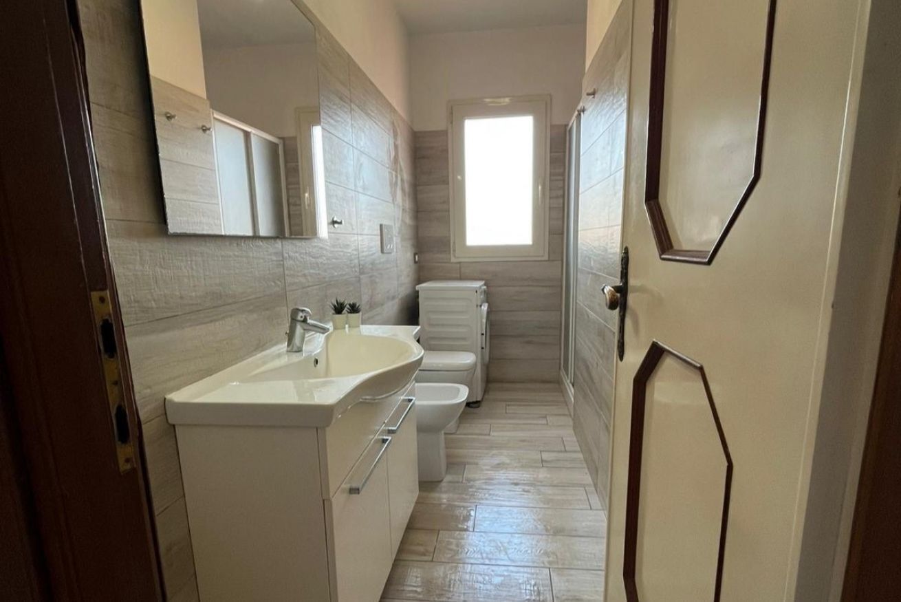 Een kleine badkamer met een wit wastafel, toilet en spiegel.