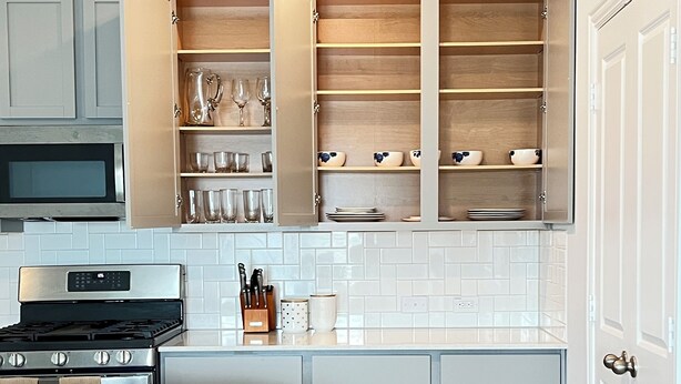 A modern kitchen with grey cabinets, a stainless steel stove, and a trash bin. - Ultimate  retreat gateway (Rosharon)