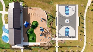 An aerial view of a park with a basketball court, playground equipment, and a building with a sloped roof. - Ultimate  retreat gateway (Rosharon)