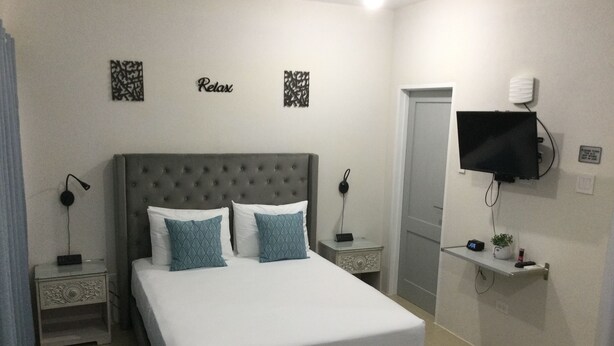 A bedroom with a large bed, two nightstands, a TV, and a door.