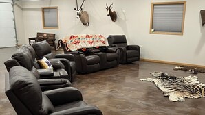 Sala de estar com sofá seccional, poltrona reclinável e tapete de zebra.