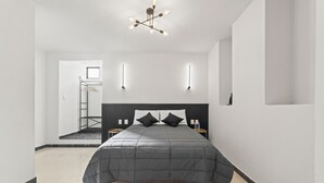 A modern bedroom with a large bed, a wooden headboard, and a ceiling light fixture. - Hotel Boutique Árbol de la Vida (Taxco)
