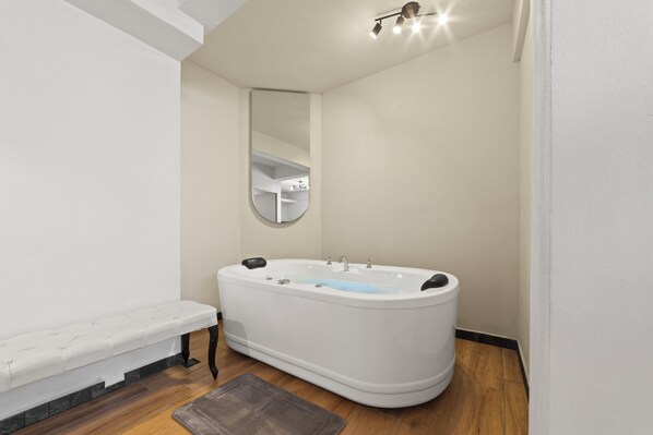 A modern bathroom with a freestanding bathtub, a bench, and a mirror.