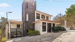 A modern two-story house with a stone facade, a tiled roof, and a gated entrance. - Hotel Boutique Árbol de la Vida (Taxco)