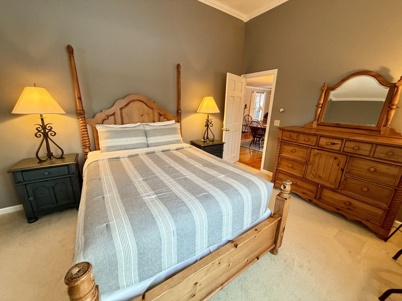 Un dormitorio con una cama grande, dos mesitas de noche con lámparas, un aparador de madera y un espejo.