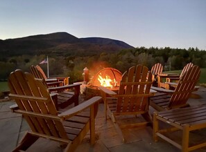 Un foyer extérieur entouré de chaises, installé sur une terrasse offrant une vue sur une montagne.