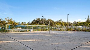 Een leeg strandvolleybalveld met een net, banken en een blauwe constructie op de achtergrond.