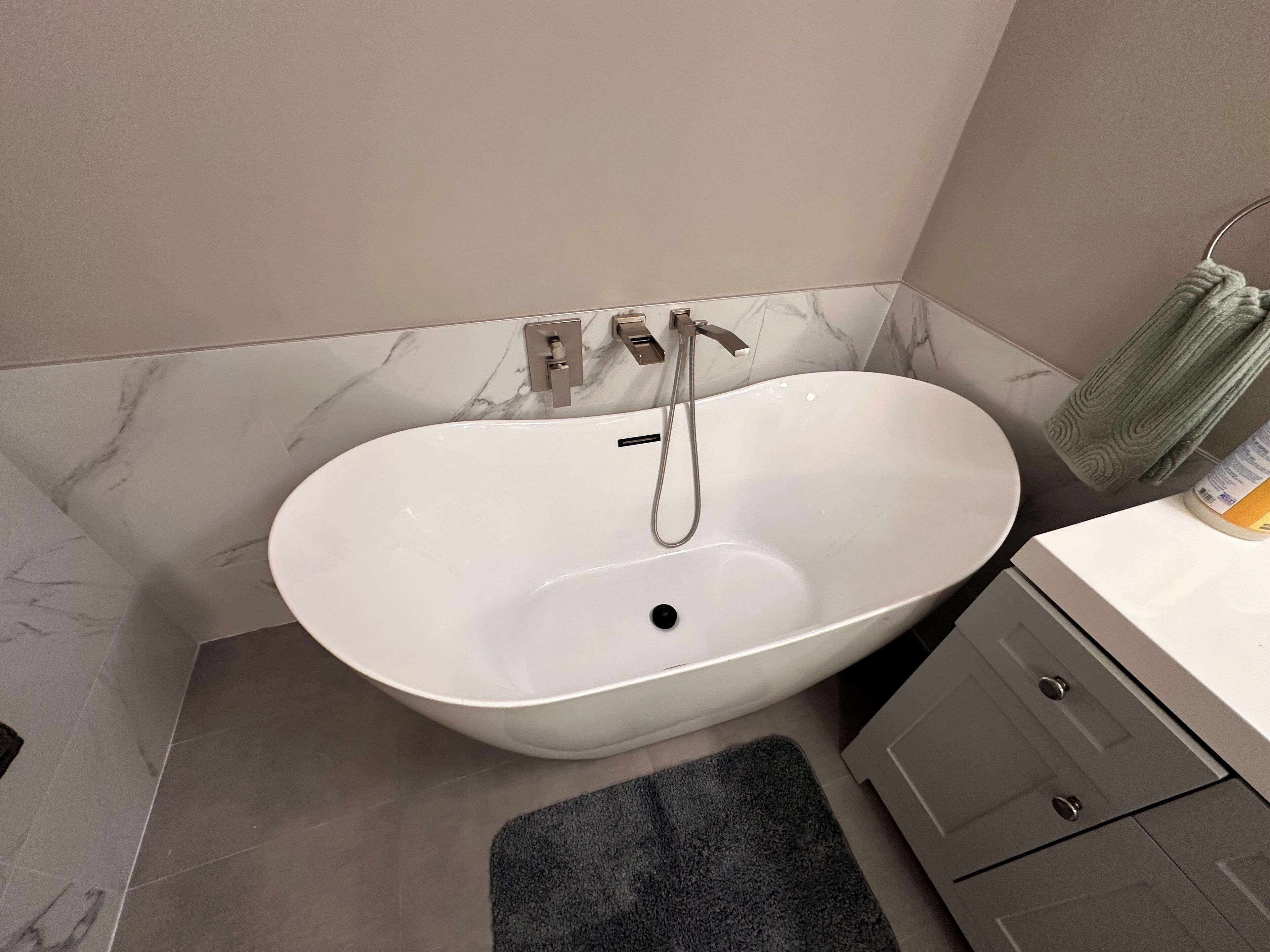 A bathroom with a freestanding bathtub, a towel rack with a towel, and a bottle of shampoo.