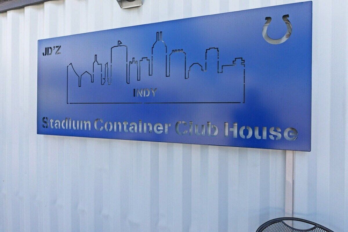 A sign for the Stadium Container Club House with a city skyline silhouette and the name 'INDY'.