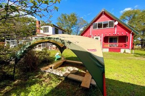 Un edificio rosso con tetto verde, una struttura in legno di fronte e un cielo azzurro limpido.