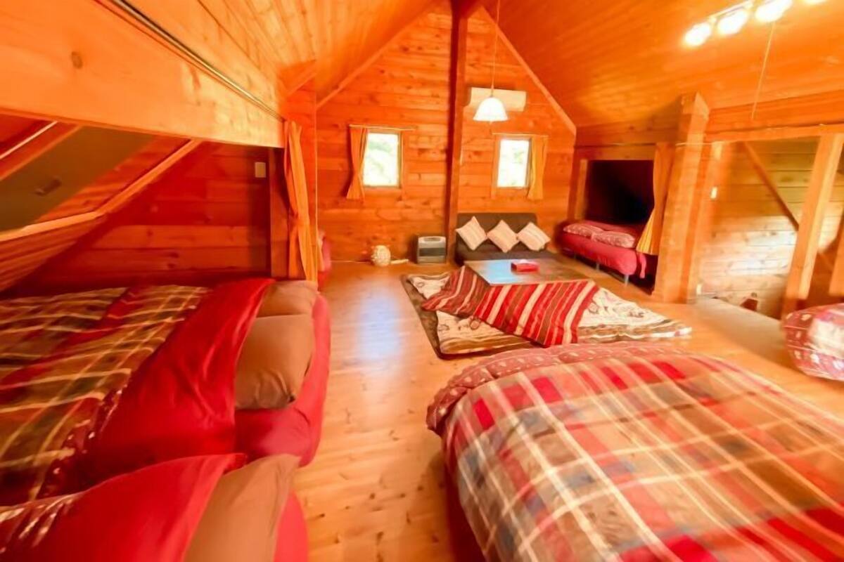 Une cabane en bois chaleureuse, avec deux lits, un canapé et une petite table.