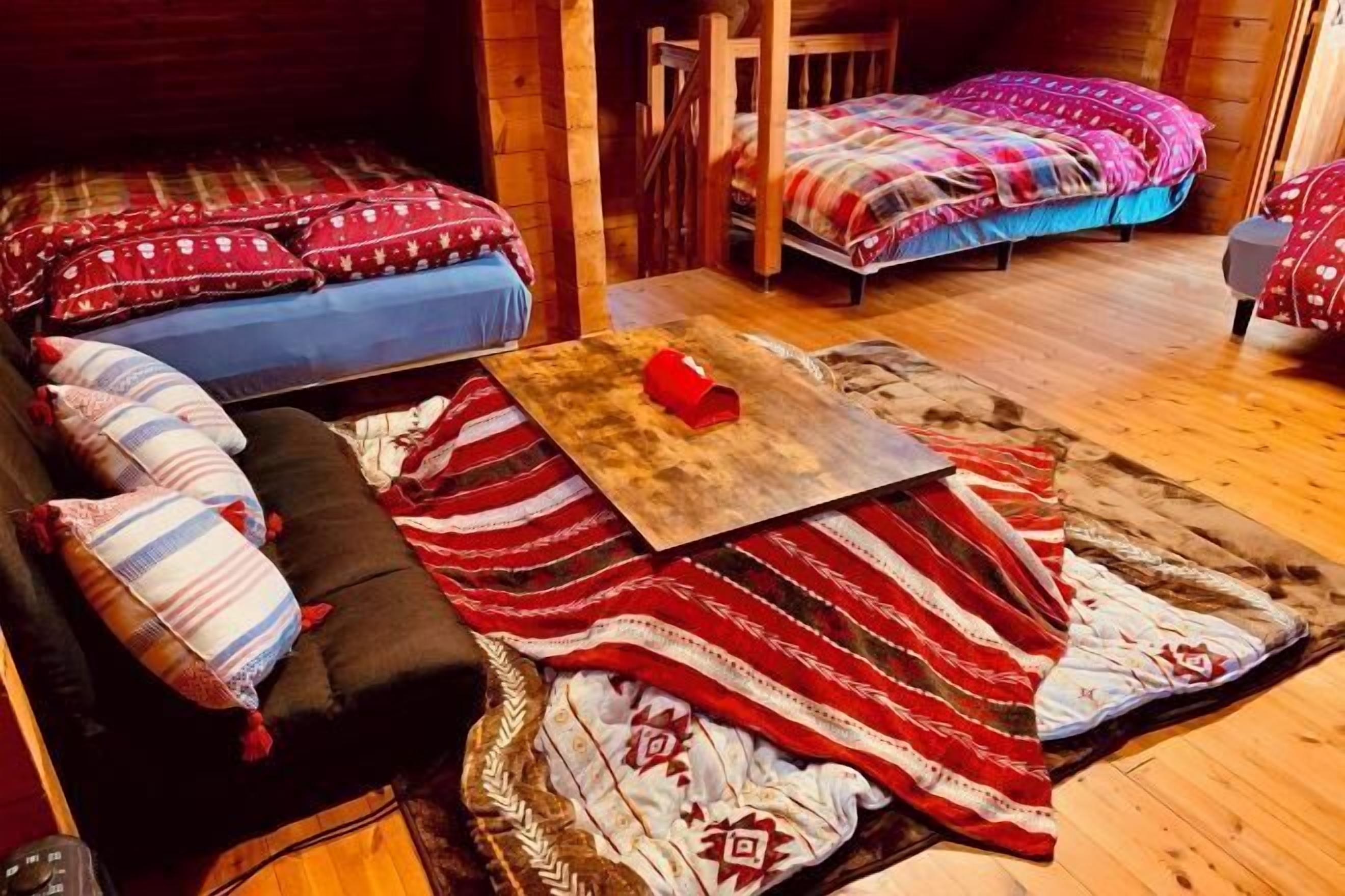 Ein gemütliches Blockhauszimmer mit zwei Betten, einer Couch und einem Couchtisch.