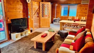 A wooden interior with a television, sofa, and a dining area.