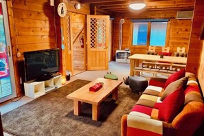 Ein Holzinnenraum mit Fernseher, einer Couch und einem Essbereich.