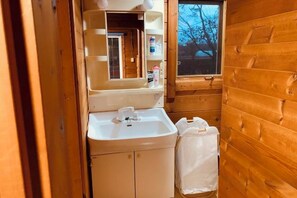 Ein kleines Badezimmer mit Waschbecken, Spiegel und Holzwänden.