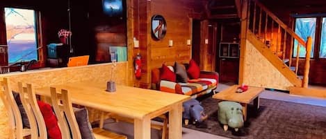 Ein Holzinnenraum mit einem Esstisch, Stühlen, einer Couch und einer Treppe.