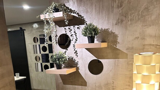 Un intérieur moderne avec un plancher en bois, une  étagère murale agrémentée de plantes et un luminaire original.