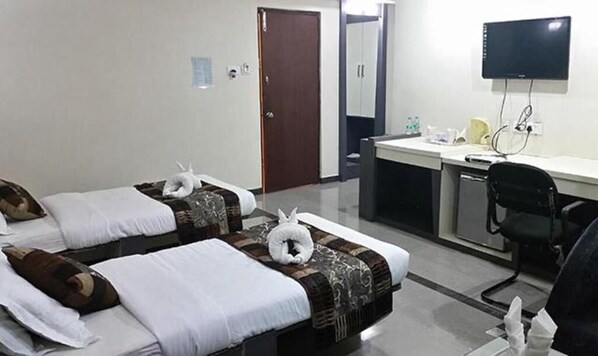 A hotel room with two beds, a desk, a chair, and a TV. - VORA CORPORATE INN (Nagpur)