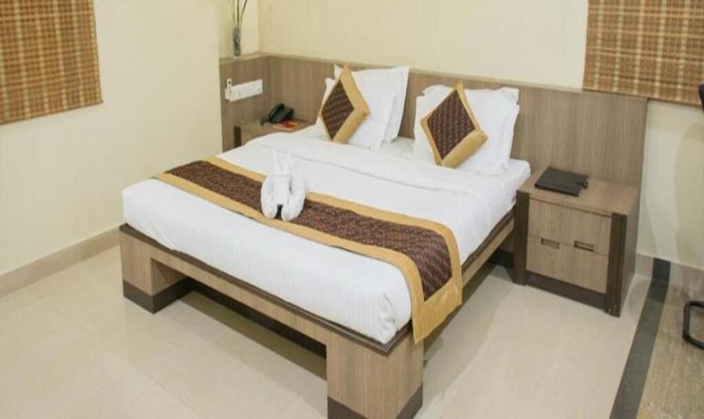Una habitación de hotel con una cama grande, una mesita de noche y una mesilla.