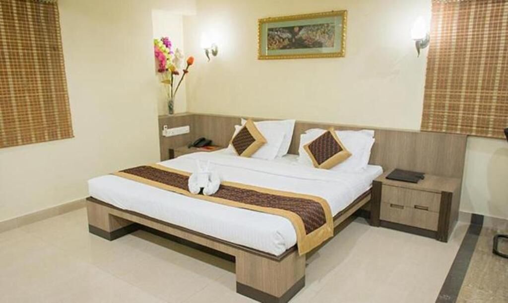 A neatly made bed with a brown and white bedspread, a bedside table with a lamp, and a wall-mounted picture.
